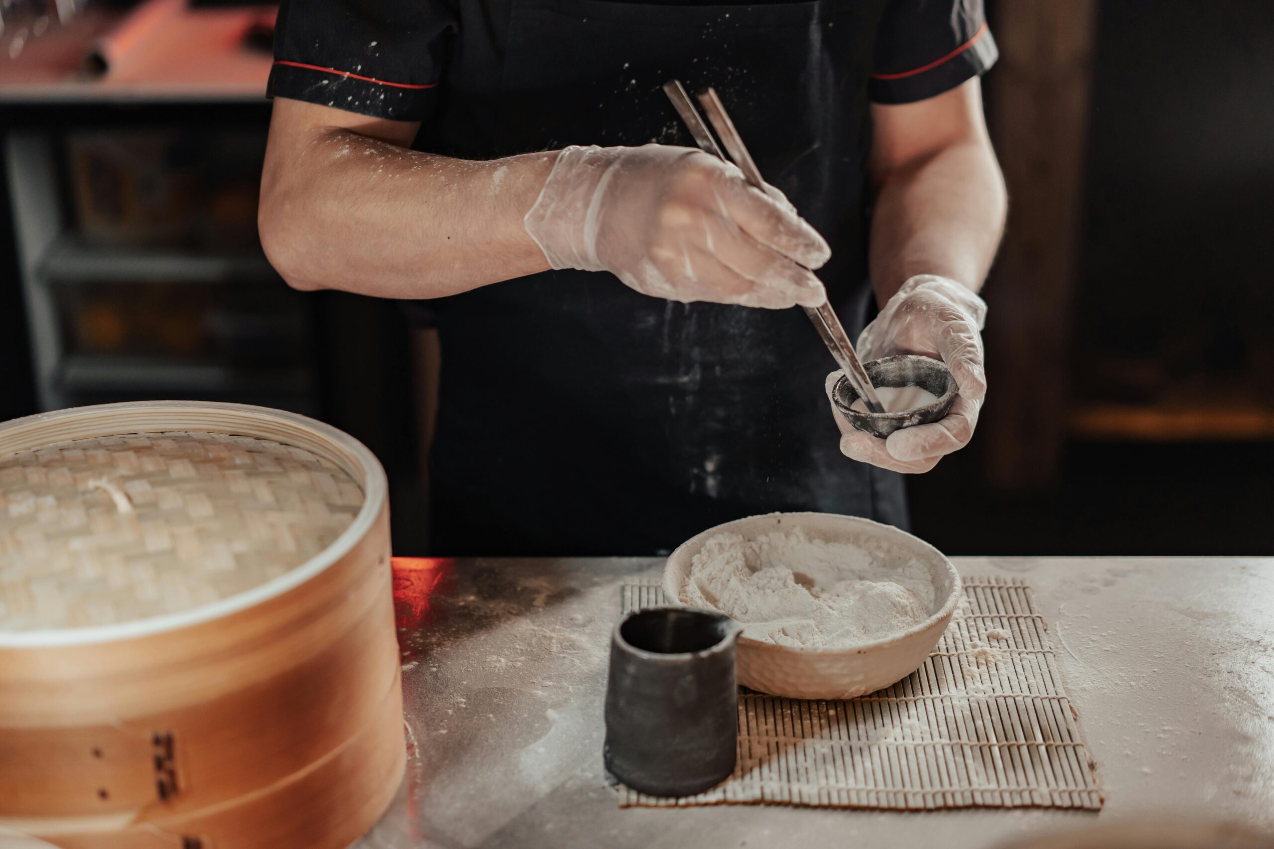 Chef uses chopsticks to prepare dumplings, showcasing traditional culinary skills in an indoor kitchen.